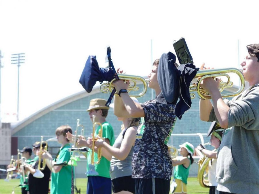 Though the marchers maintain a six-foot distance, woodwinds and brass use bell covers to reduce the spread of germs.